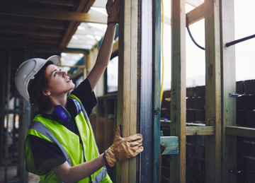 A construction worker assessing a wooden beam
